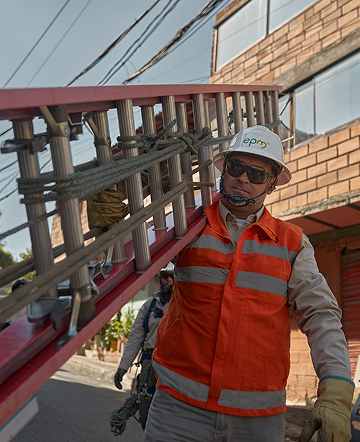 Trabajador de EPM transporta una escalera durante labores de mantenimiento en redes eléctricas urbanas