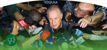 Fotografía del gerente general de EPM John Maya, habla mientras es rodeado por numerosos periodistas que le acercan micrófonos, grabadoras y teléfonos móviles