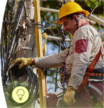 Funcionario de EPM realiza mantenimiento sobre poste de energía eléctrica, acompañado de un icono de bombilla