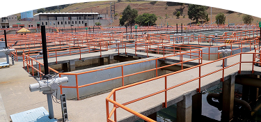 Planta de tratamiento de agua con pasarelas de concreto y barandillas naranjas.