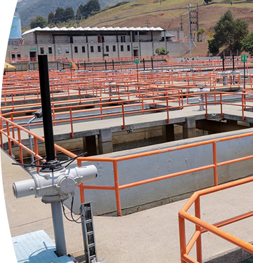 Planta de tratamiento de agua con pasarelas de concreto y barandillas naranjas.