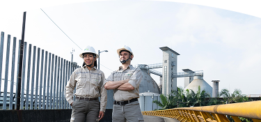 Fotografía de dos trabajadores de EPM y de fondo una planta