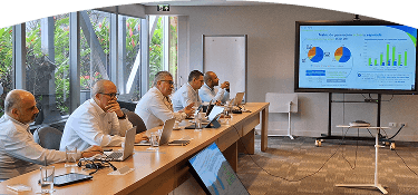 Equipo de trabajo en reunión analizando indicadores y gráficos de generación en una pantalla, en entorno corporativo.