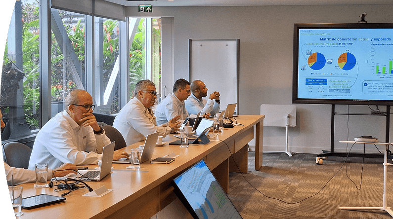 Equipo de trabajo en reunión analizando indicadores y gráficos de generación en una pantalla, en entorno corporativo.