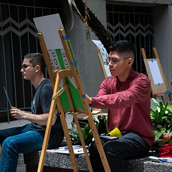 Personas realizando actividades de pintura artística en caballetes durante una jornada cultural