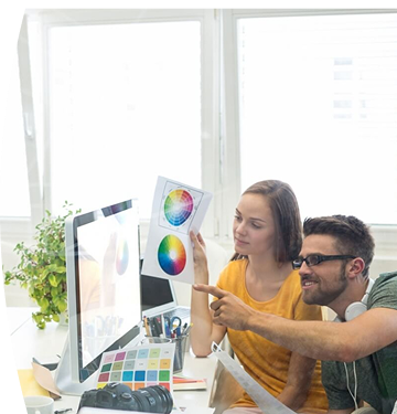 Equipo creativo revisando paletas de colores frente a una computadora, en una reunión de diseño publicitario en oficina moderna.