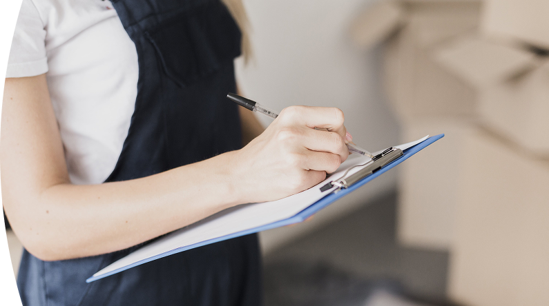 Persona escribiendo con bolígrafo en una hoja sujetada por un portapapeles azul