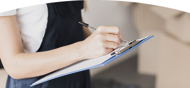 Persona escribiendo con bolígrafo en una hoja sujetada por un portapapeles azul