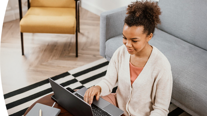Persona sentada en una sala de estar trabajando en un computador portátil sobre una mesa baja
