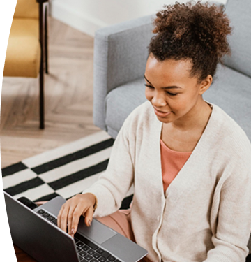 Persona sentada en una sala de estar trabajando en un computador portátil sobre una mesa baja