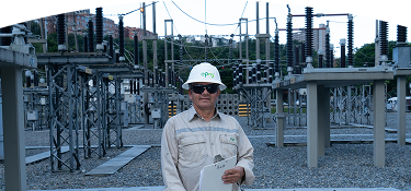 Trabajador de EPM parado en una planta eléctrica con un portapapeles en la mano