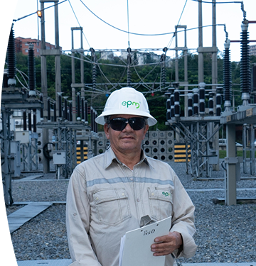 Trabajador de EPM parado en una planta eléctrica con un portapapeles en la mano