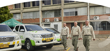 Dos empleados EPM caminando frente unas camionetas de EPM
