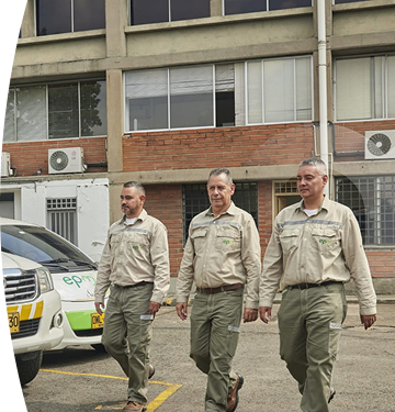 Dos empleados EPM caminando frente unas camionetas de EPM