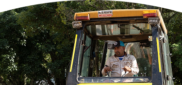Operario de EPM maneja maquinaria pesada en campo, usando uniforme y gorra, en labores de mantenimiento de infraestructura pública