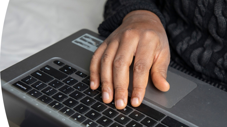Persona con suéter oscuro usa portátil apoyando su mano en el teclado