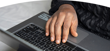 Persona con suéter oscuro usa portátil apoyando su mano en el teclado