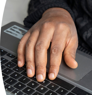 Persona con suéter oscuro usa portátil apoyando su mano en el teclado