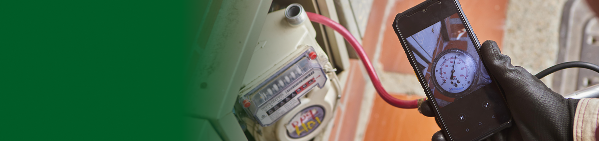 Persona revisando un medidor de gas y registrando la lectura con un celular durante la revisión periódica de gas