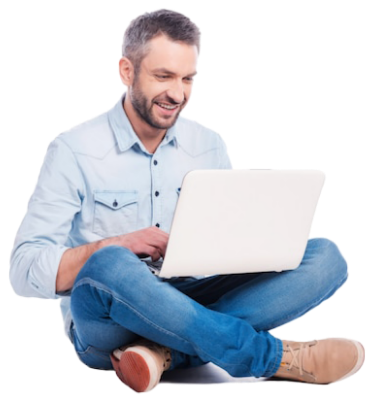 Hombre con camisa clara y jeans sonríe mientras usa un computador portátil, sentado con las piernas cruzadas sobre un fondo blanco