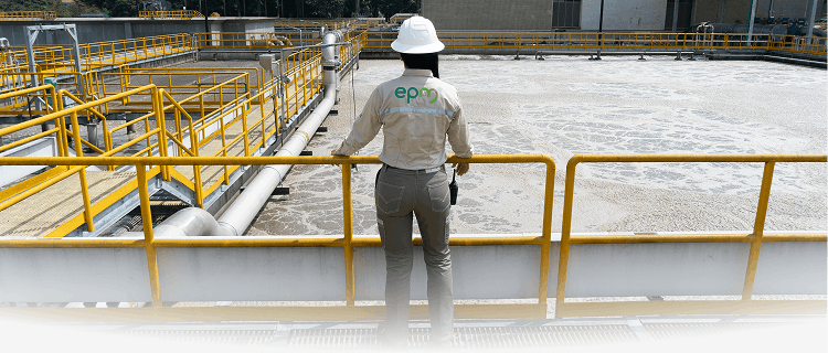 Trabajadora de EPM con casco blanco observa desde una baranda el proceso de tratamiento