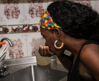 Mujer bebiendo agua desde al llave
