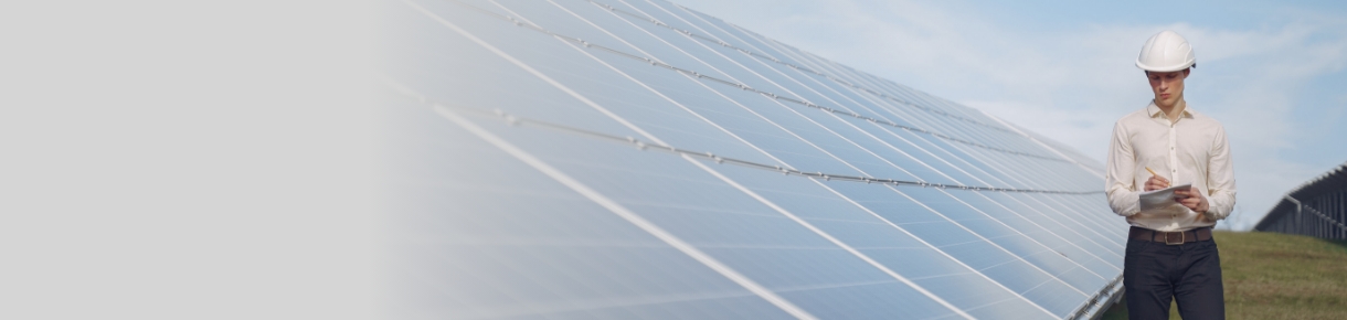 Conoce todas las preguntas frecuentes sobre el proceso de los Autogeneradores. El acceso a este contenido está acompañado de un hombre con casco blanco y camisa clara revisando documentos frente a una instalación de paneles solares