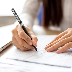 Persona escribiendo con bolígrafo sobre un documento