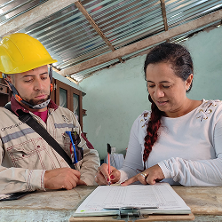 Funcionario de epm acompaña a mujer que diligencia formato de solicitud del servicio de energía prepago
