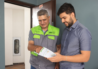 Empleado de EPM en uniforme revisando una factura de servicios públicos con un ciudadano