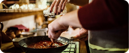 Persona cocinando carne mientras le pone sal