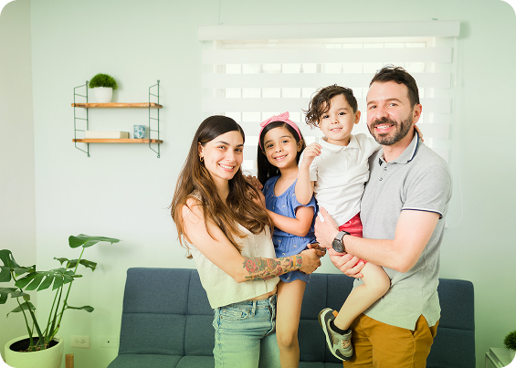 Familia de cuatro integrantes sonriendo en la sala de su hogar