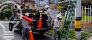Trabajadores con cascos, sacando conos viales de una camioneta, en una calle de la ciudad.