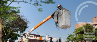 Operario EPM en camión canasta realizando mantenimiento de líneas eléctricas y poda de árboles