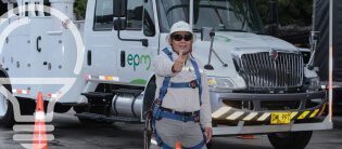 Imagen de un técnico de EPM saludando con el dedo pulgar, con una camioneta de la compañía al fondo.