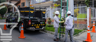  Operarios de EPM instalando escalera en poste de energía junto a camioneta y conos de seguridad en zona residencial