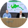 Dos personas en una rueda de prensa de EPM, sentadas frente a un mapa proyectado en pantalla