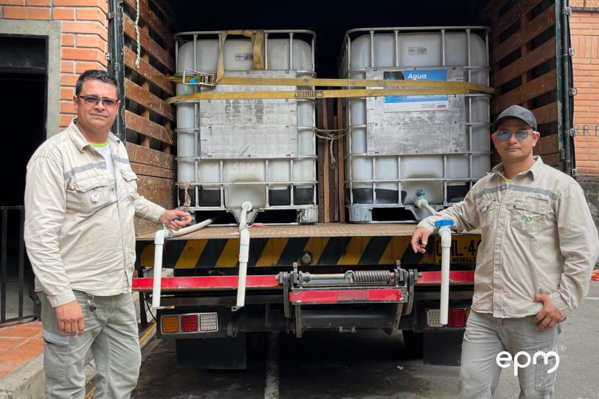 Fotografía de trabajadores de EPM junto a un camión con contenedores de almacenamiento de agua o líquidos.