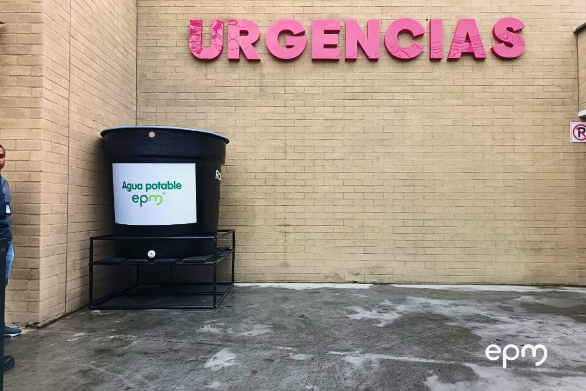 Fotografía de un tanque negro de almacenamiento de agua con el logo de EPM, ubicado fuera de una sala de urgencias.