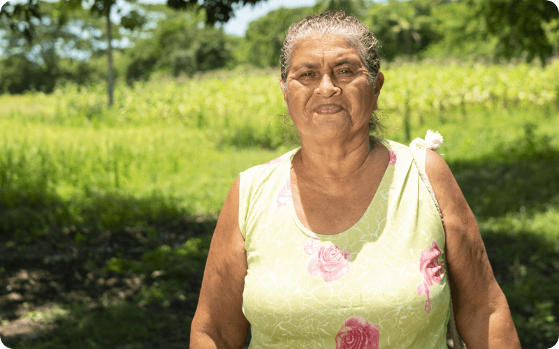 Fotografía de mujer mayor sonriendo a la cámara en un paisaje rural