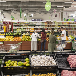 Personas comprando frutas y verduras en supermercado con amplia oferta de productos frescos