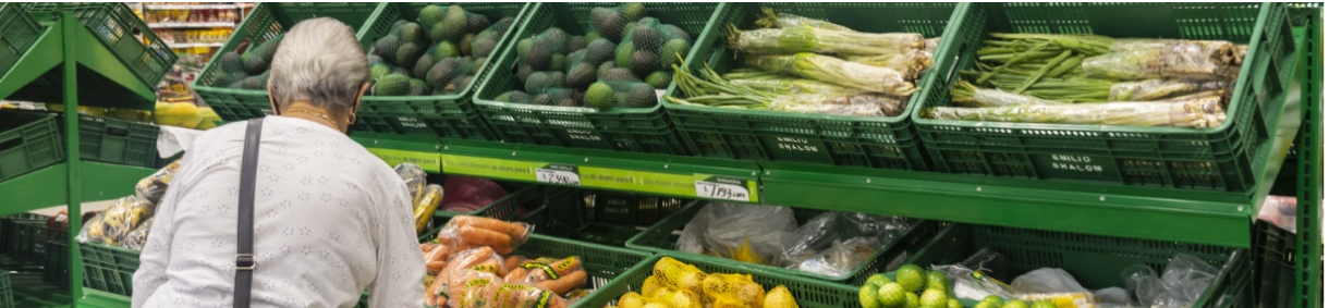 Mujer eligiendo verduras frescas como aguacates, zanahorias y cebollas en un supermercado