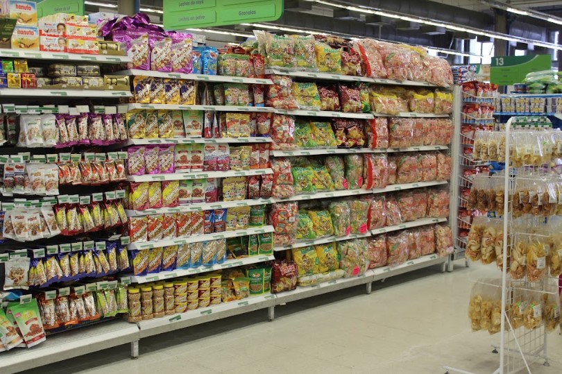 Pasillo con productos de mecatos y dulces en estantes bien organizados