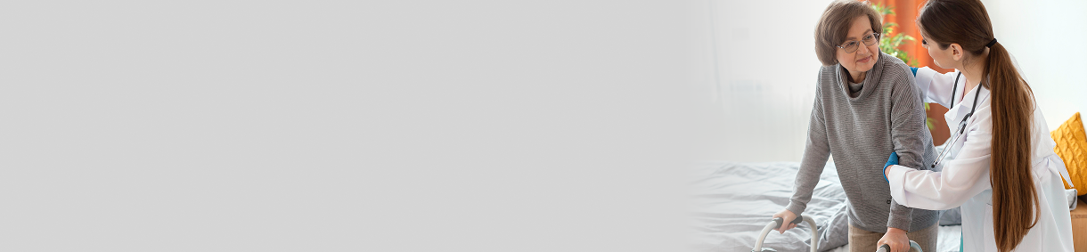 Doctora apoya a una mujer mayor que usa caminador, sosteniéndola del brazo