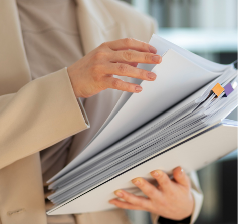 Doctor con bata blanca sosteniendo una carpeta con documentos y un bolígrafo en la mano.