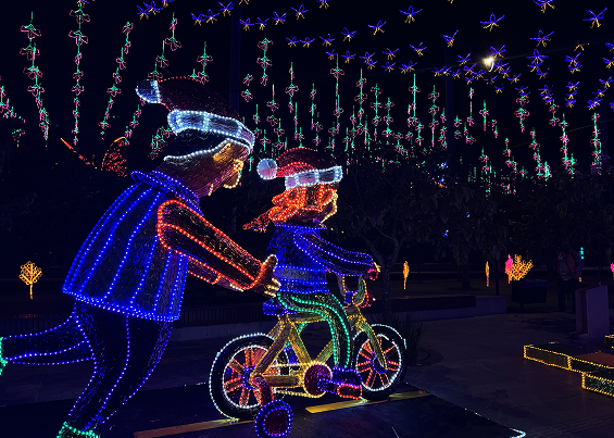 Alumbrado de padre enseñándole a su hija a montar en bicicleta