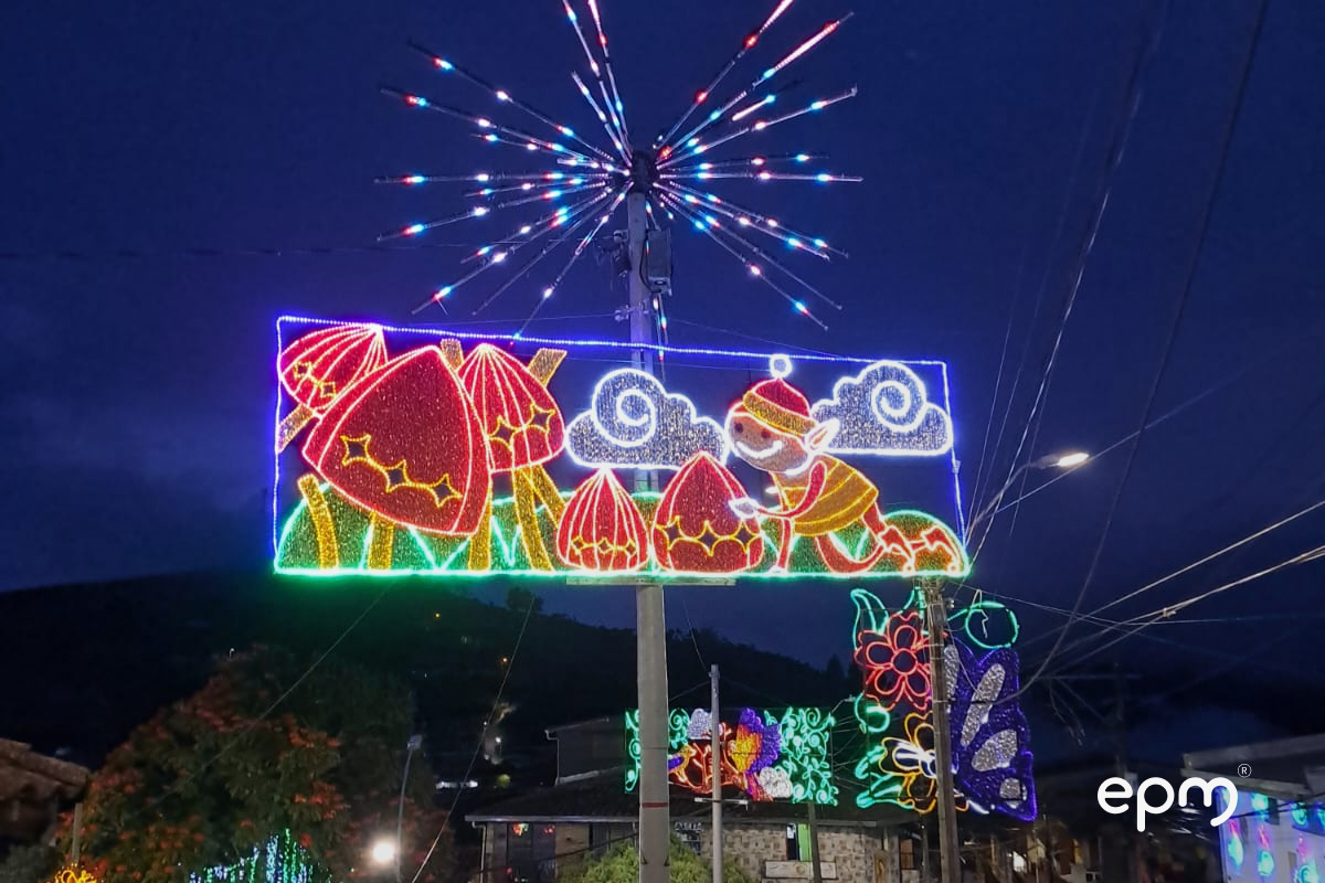 Fotografía de figura navideña en poste de energía. Se observan figuras en color rojo, verde y gris