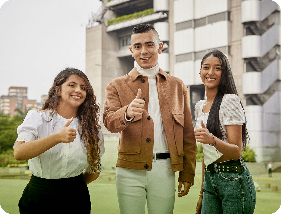 Grupo de tres jóvenes sonriendo y mostrando el gesto de pulgar arriba, de pie frente a el edificio epm, transmitiendo confianza y positivismo.