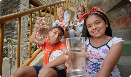 Fotografía de niños felices mostrando vasos de agua a la cámara 