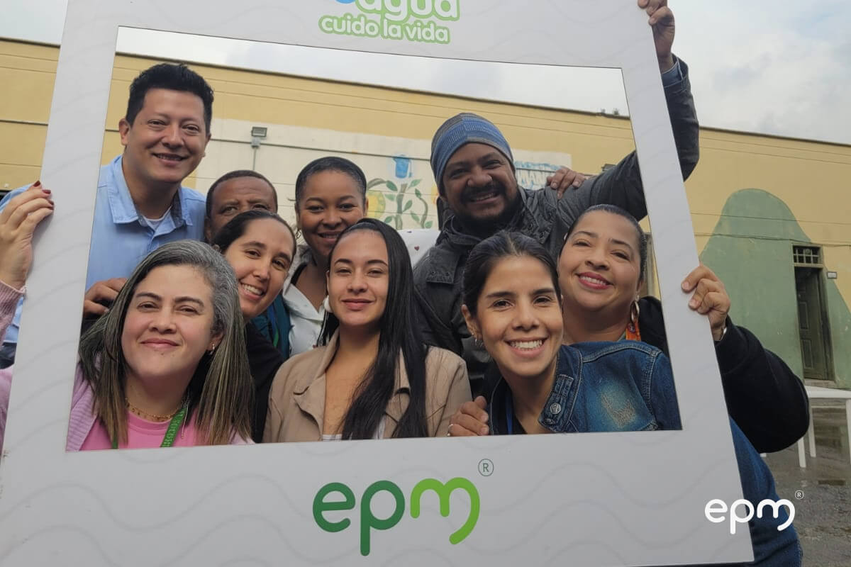 Fotografía de trabajadores de EPM sosteniendo un marco de fotos el cual tiene el logo de " Cuido El Agua, Cuido la Vida" en la parte superior, y el logo de epm en la parte inferior.